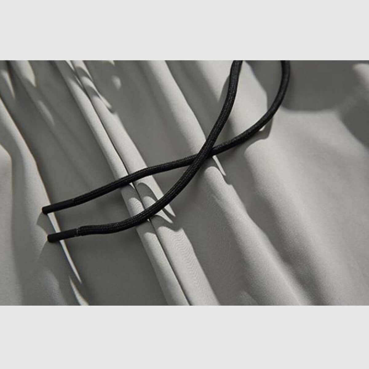 Close-up of adjustable black drawstring on side stripe sweatpants, showcasing soft fabric texture.