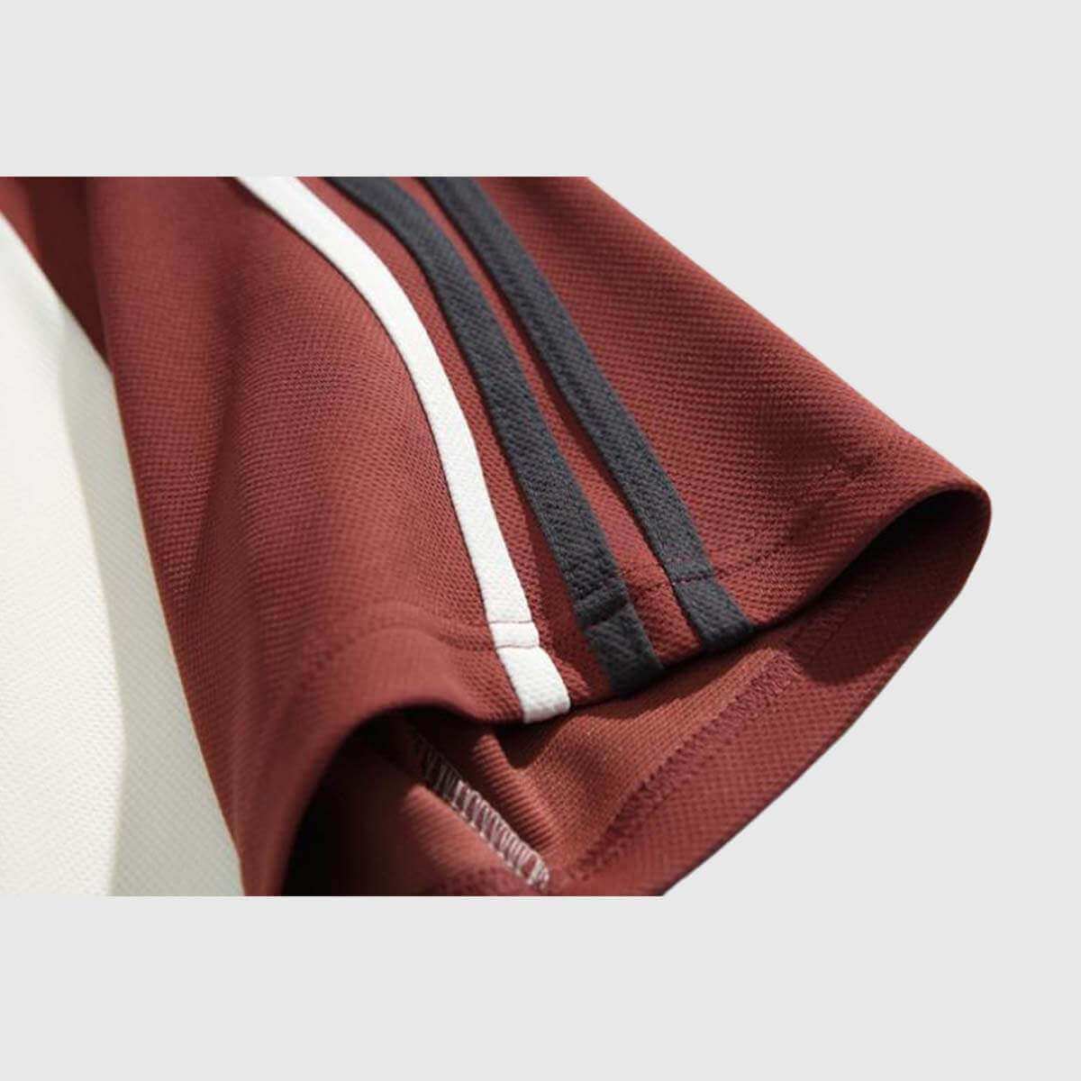 Close-up of a vintage graphic raglan shirt sleeve featuring bold stripes in maroon, white, and black for a stylish look.