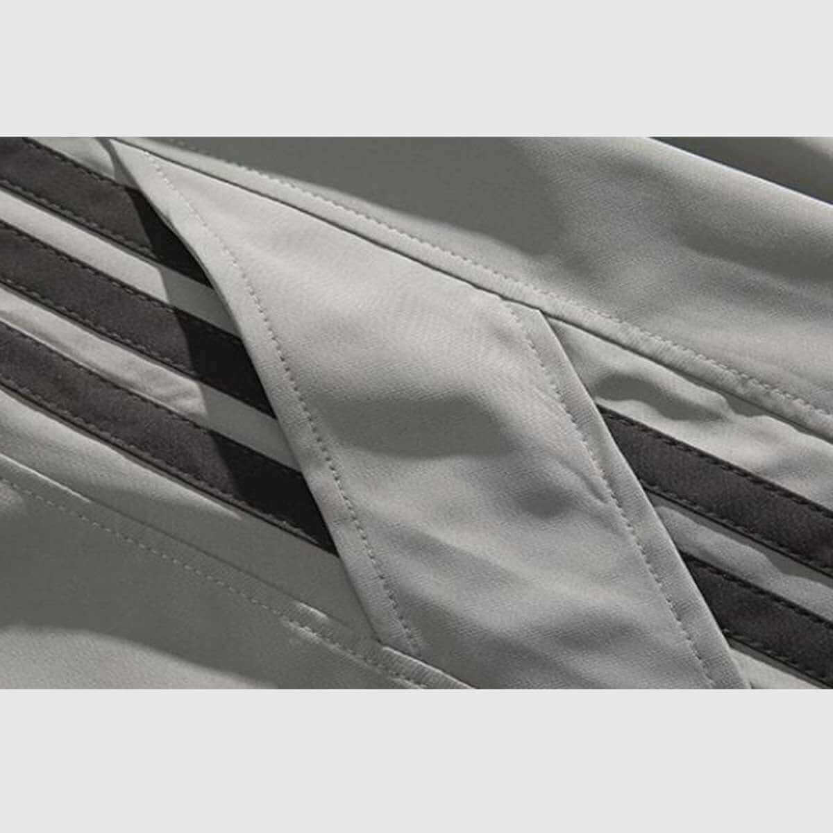 Close-up of side stripe detail on sweatpants, showcasing sporty black stripes on a soft gray fabric.